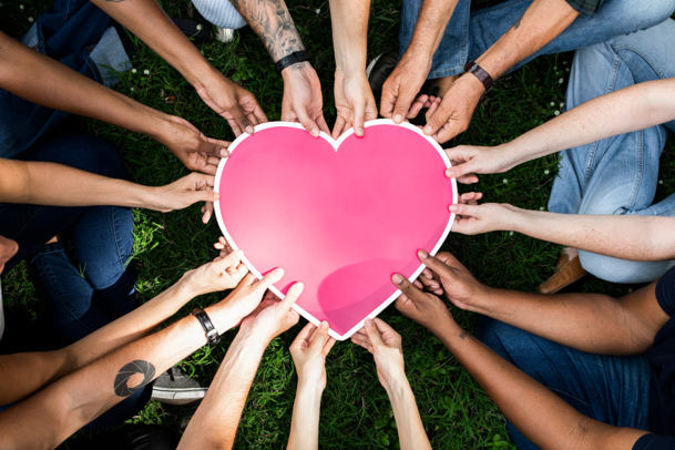 Photo image of many hands holding a paper heart